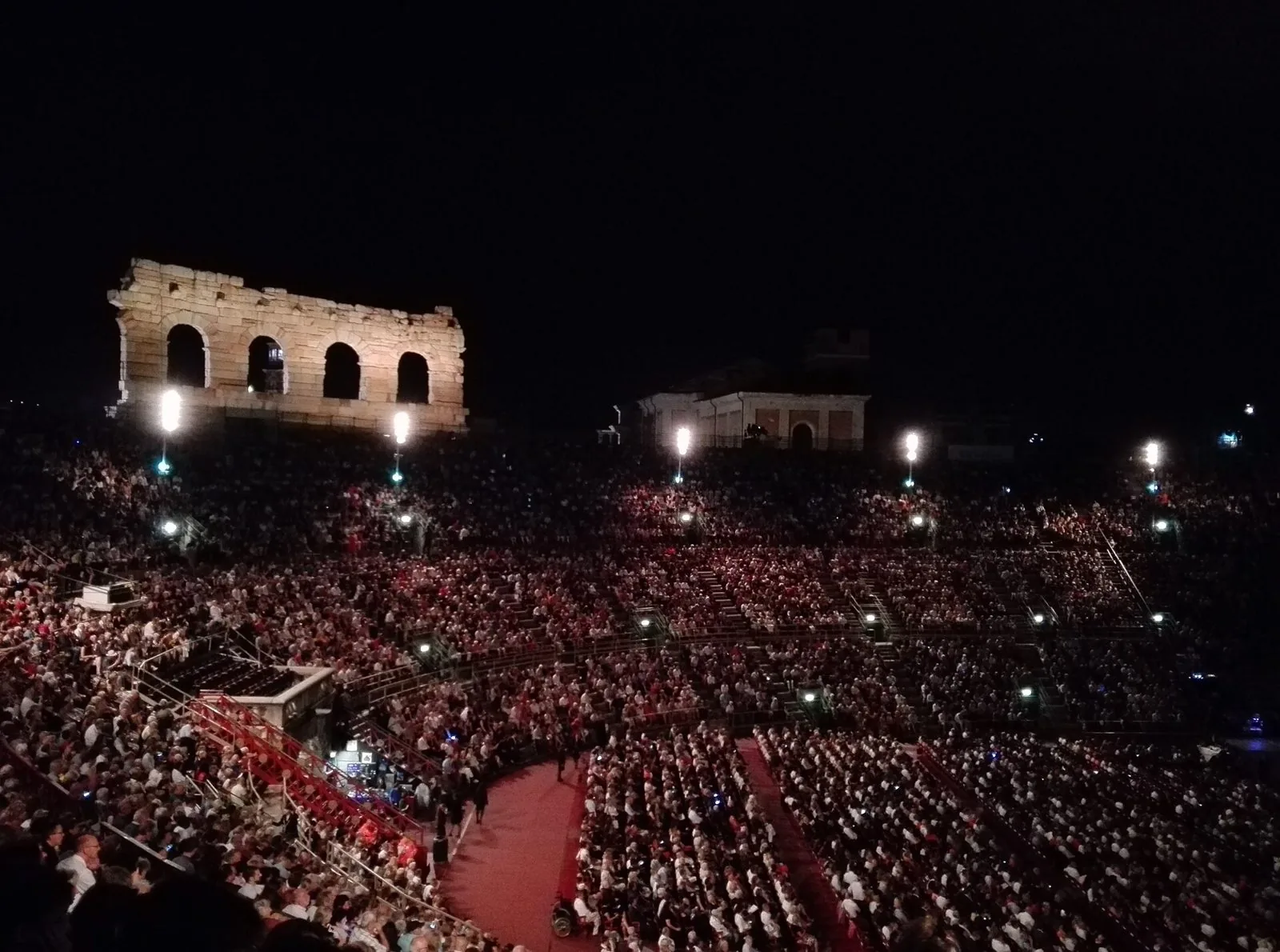 L'interno dell'Arena di Verona gremito di pubblico di sera durante una rappresentazione lirica