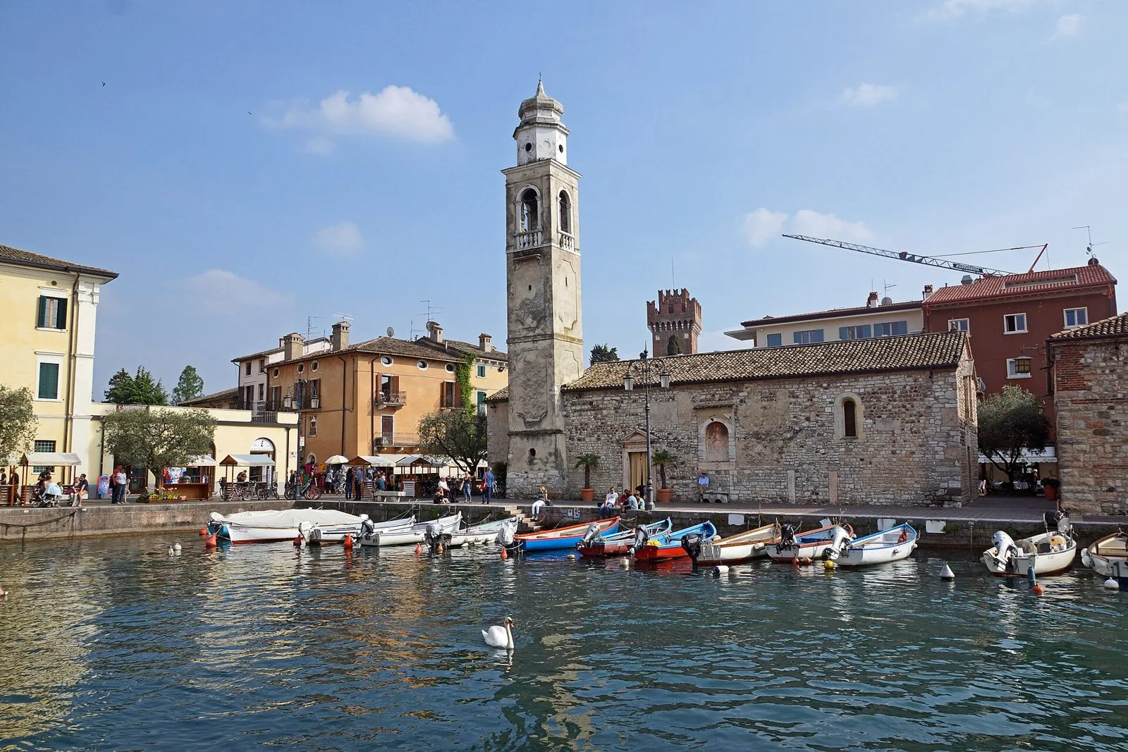 Il porto antico di Lazise con le barche, la chiesa di San Nicolò con il campanile e una torre del castello sullo sfondo