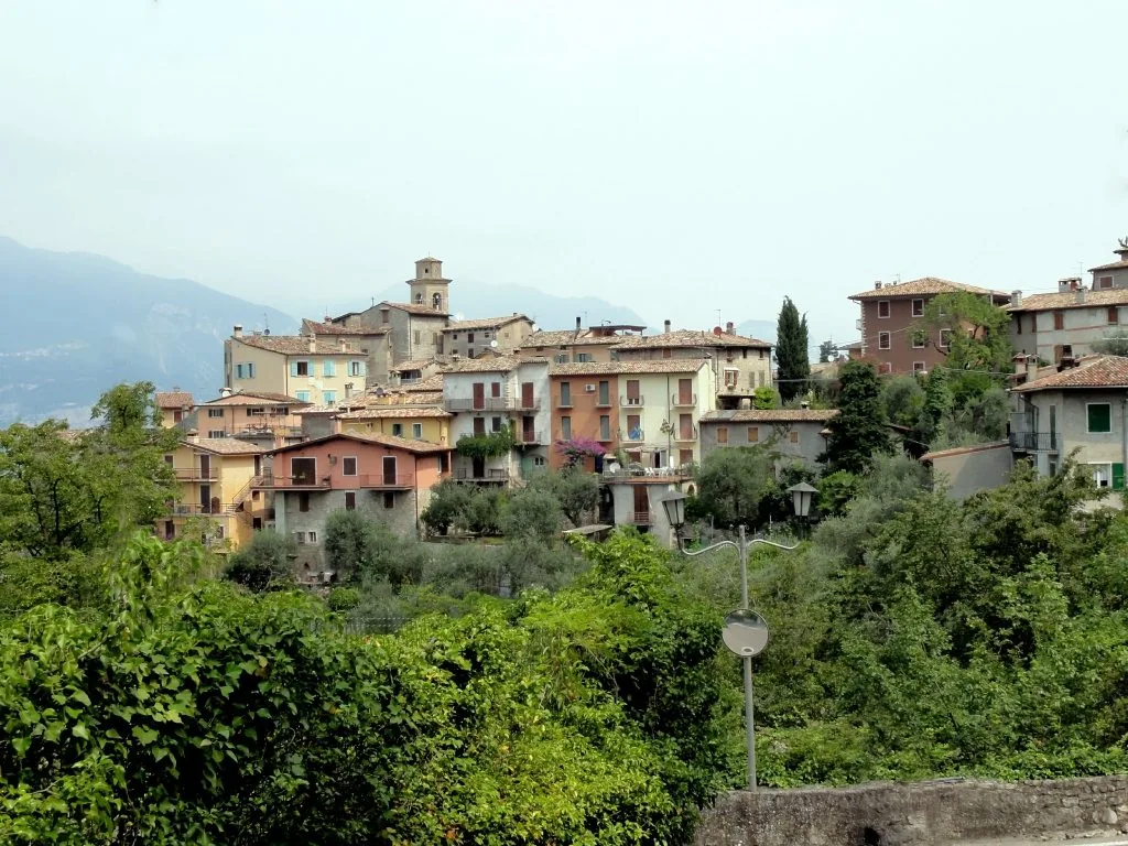 Le case del borgo di Pai di Sopra tra il verde, con le montagne del Garda sullo sfondo