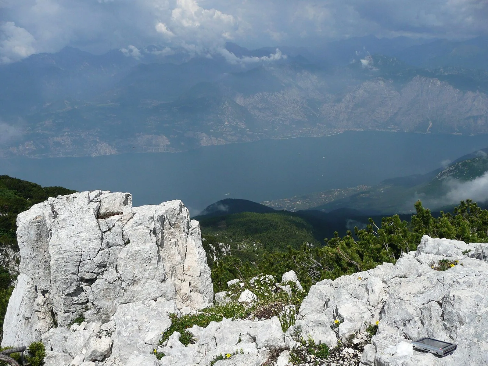 Rocce calcaree e pini mughi sulla cresta del Monte Baldo, con il Lago di Garda e le montagne della sponda opposta